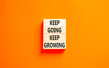 Keep going and growing symbol. Concept words phrase Keep going keep growing on beautiful wooden blocks. Beautiful orange paper background. Business Keep going and growing concept. Copy space.の写真素材