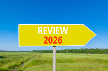 Review 2026 symbol. Concept words Review 2026 on beautiful yellow road sign. Beautiful green grass field forest and blue sky background. Business and review 2026 concept. Copy space.の写真素材
