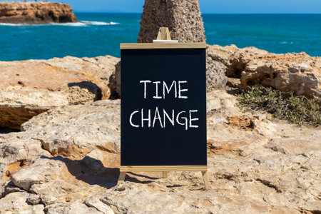 Time change symbol. Concept word Time change on beautiful black blackboard. Beautiful stone and blue...