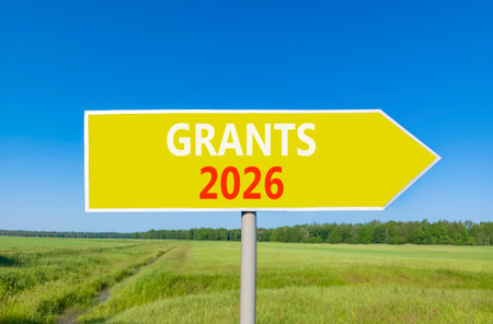 Grants 2026 symbol. Concept words Grants 2026 on beautiful yellow road sign. Beautiful green grass...