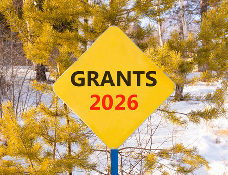 Grants 2026 symbol. Concept words Grants 2026 on beautiful yellow road sign. Beautiful winter forest...