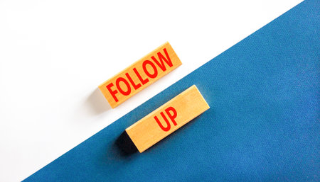 Follow up symbol. Concept word Follow up on beautiful wooden blocks. Beautiful white and blue paper background. Business follow up concept. Copy space.の写真素材
