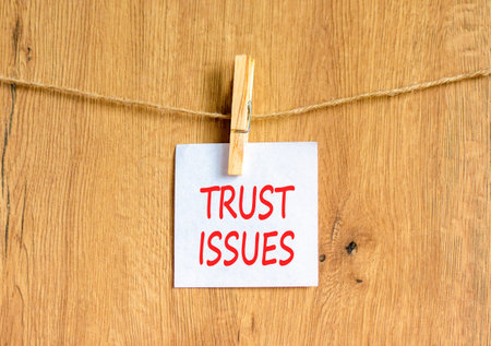 Trust issues symbol. Concept word Trust issues on beautiful white paper. Beautiful wooden...