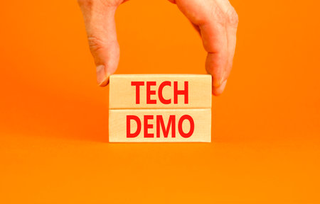 Tech demo symbol. Concept word Tech demo on beautiful wooden blocks. Beautiful orange paper background. Businessman's hand. Business tech demo concept. Copy space.の写真素材