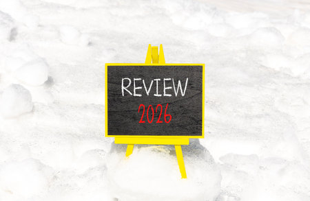 Review 2026 symbol. Concept words Review 2026 on beautiful black blackboard. Beautiful white snow...