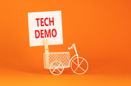 Tech demo symbol. Concept word Tech demo on beautiful white paper. Beautiful wooden clothespin. Miniature white bicycle. Beautiful orange background. Business tech demo concept. Copy space.の写真素材