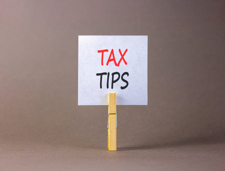 Tax tips symbol. Concept word Tax tips on beautiful white paper. Beautiful wooden clothespin. Beautiful gray background. Business tax tips concept. Copy space.の写真素材