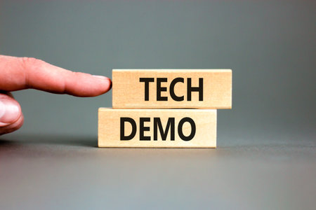 Tech demo symbol. Concept word Tech demo on beautiful wooden blocks. Beautiful gray paper background. Businessman's hand. Business tech demo concept. Copy space.の写真素材