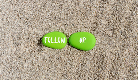 Follow up symbol. Concept word Follow up on beautiful green stones. Sea sand beach. Beautiful sand beach background. Business follow up concept. Copy space.の写真素材
