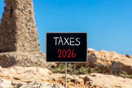 Taxes 2026 new year symbol. Concept words Taxes 2026 on beautiful black blackboard. Beautiful stone and blue sky background. Business and taxes 2026 new year concept. Copy space.の写真素材