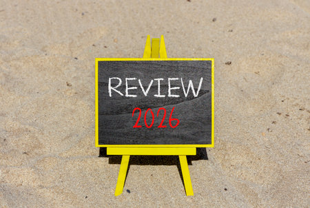 Review 2026 symbol. Concept words Review 2026 on beautiful black blackboard. Beautiful sand beach background. Business and review 2026 concept. Copy space.の写真素材