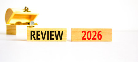 Review 2026 symbol. Concept words Review 2026 on beautiful wooden blocks. Beautiful white paper background. Beautiful wooden chest with coins. Business and review 2026 concept. Copy space.の写真素材