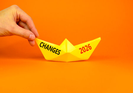 Changes 2026 symbol. Concept words Changes 2026 on beautiful yellow paper boat. Beautiful orange paper background. Businessman's hand. Business and changes 2026 concept. Copy space.の写真素材