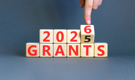 2026 Grants symbol. Concept words 2026 Grants on beautiful wooden blocks. Beautiful gray paper background. Businessman's hand. Business and 2026 grants concept. Copy space.の写真素材