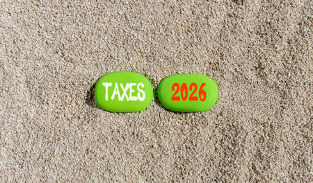 Taxes 2026 new year symbol. Concept words Taxes 2026 on beautiful green stones on sand beach....