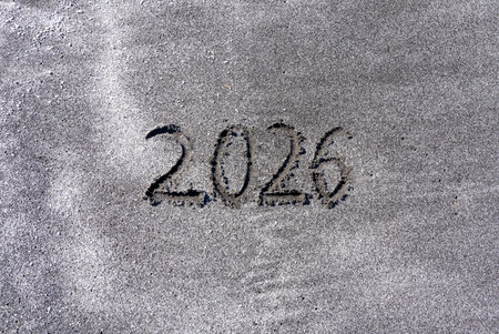 Concept 2026 happy new year written on ocean sand. Ocean sand background, copy space.