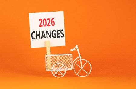 2026 Changes symbol. Concept words 2026 Changes on beautiful white paper on wooden clothespin. Beautiful orange background. Beautiful miniature bicycle. Business and 2026 changes concept. Copy space.の写真素材
