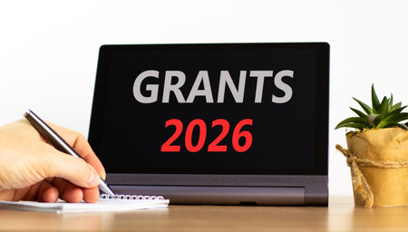 Grants 2026 symbol. Concept words Grants 2026 on beautiful black tablet screen. Beautiful white background. Businessman's hand. Business and grants 2026 concept. Copy space.の写真素材