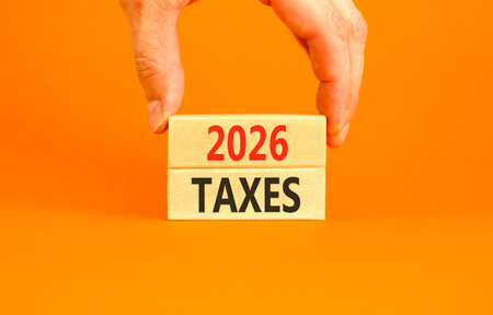 2026 taxes new year symbol. Concept words 2026 taxes on beautiful wooden blocks. Beautiful orange paper background. Businessman's hand. Business and 2026 taxes new year concept. Copy space.の写真素材