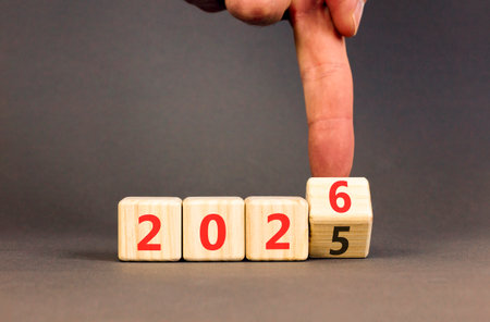 Business concept of 2026 new year symbol. Businessman turns wooden cube and changes number 2025 to...