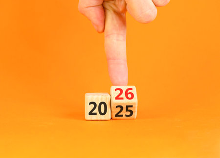Business concept of 2026 new year symbol. Businessman turns wooden cube and changes number 2025 to...