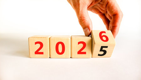 Business concept of 2026 new year symbol. Businessman turns wooden cube and changes number 2025 to...