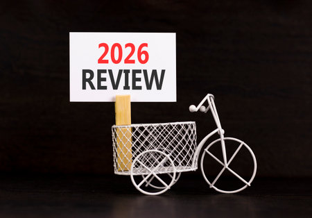2026 Review symbol. Concept words 2026 Review on beautiful white paper on wooden clothespin. Beautiful black background. Beautiful miniature bicycle. Business and 2026 review concept. Copy space.の写真素材