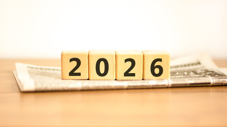 Business concept of 2026 new year symbol. Beautiful wooden cubes on newspaper with number 2026 Happy...