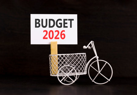 Budget 2026 symbol. Concept words Budget 2026 on beautiful white paper on wooden clothespin. Beautiful black background. Beautiful miniature bicycle. Business and budget 2026 concept. Copy space.の写真素材