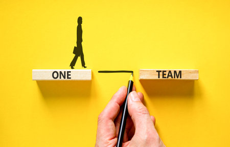 One team symbol. Concept word One team on beautiful wooden blocks. Beautiful yellow paper background. Businesswoman icon. Business one team concept. Copy space.の写真素材
