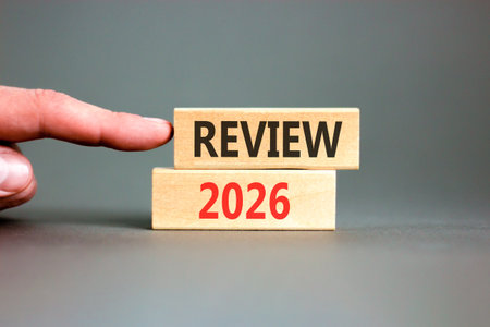 Review 2026 symbol. Concept words Review 2026 on beautiful wooden blocks. Beautiful gray paper background. Businessman's hand. Business and review 2026 concept. Copy space.の写真素材