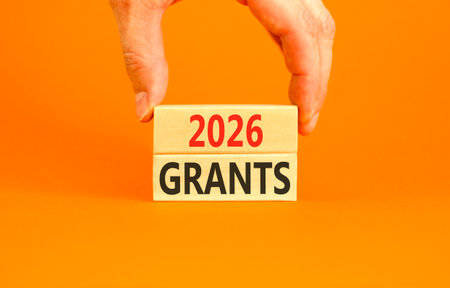2026 Grants symbol. Concept words 2026 Grants on beautiful wooden blocks. Beautiful orange paper background. Businessman's hand. Business and 2026 grants concept. Copy space.の写真素材