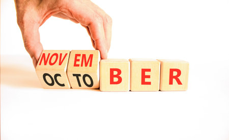 Symbol for the change from October to November. Businessman turns wooden cubes and changes the word October to November. Beautiful white background. Happy November concept. Copy space.の写真素材