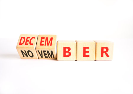 Symbol for the change from November to December. Businessman turns wooden cubes and changes the word November to December. Beautiful white background. Happy December concept. Copy space.の写真素材