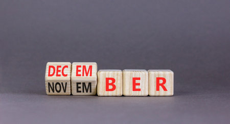 Symbol for the change from November to December. Businessman turns wooden cubes and changes the word...