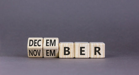 Symbol for the change from November to December. Businessman turns wooden cubes and changes the word November to December. Beautiful gray background. Happy December concept. Copy space.の写真素材