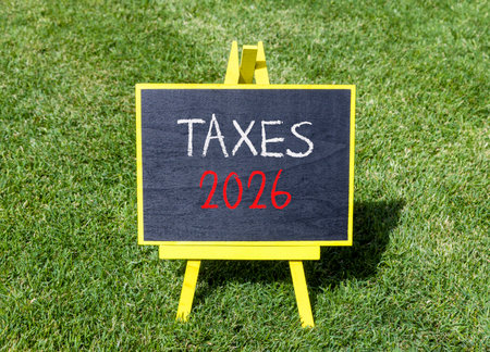 Taxes 2026 new year symbol. Concept words Taxes 2026 on beautiful black blackboard. Beautiful green...