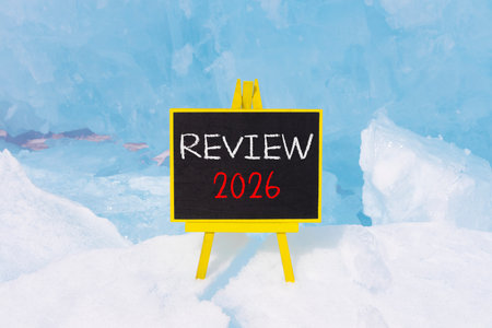 Review 2026 symbol. Concept words Review 2026 on beautiful black blackboard. Beautiful blue lake Baikal ice background. Business and review 2026 concept. Copy space.の写真素材