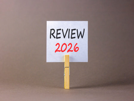 Review 2026 symbol. Concept words Review 2026 on beautiful white paper on wooden clothespin. Beautiful gray background. Business and review 2026 concept. Copy space.の写真素材
