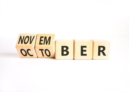 Symbol for the change from October to November. Businessman turns wooden cubes and changes the word...
