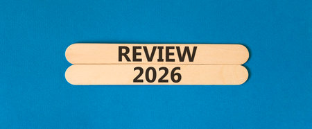 Review 2026 symbol. Concept words Review 2026 on beautiful wooden sticks. Beautiful blue paper background. Business and review 2026 concept. Copy space.の写真素材