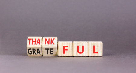 Thankful and grateful symbol. Concept words Thankful and Grateful on beautiful wooden cubes. Beautiful gray background. Business, psychological thankful and grateful concept. Copy space.の写真素材