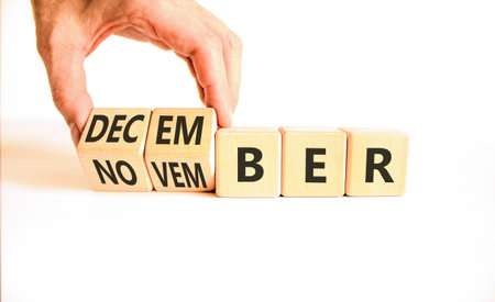Symbol for the change from November to December. Businessman turns wooden cubes and changes the word...