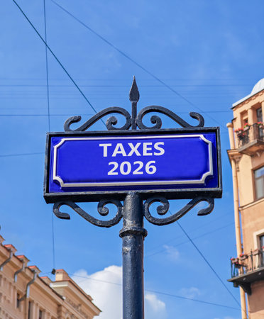 Taxes 2026 new year symbol. Concept words Taxes 2026 on beautiful blue road sign. Beautiful blue sky and buildings background. Business and taxes 2026 new year concept. Copy space.の写真素材