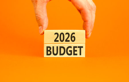 2026 Budget symbol. Concept words 2026 Budget on wooden blocks. Orange paper background. Businessman's hand. Business and 2026 budget concept. Copy space.の写真素材