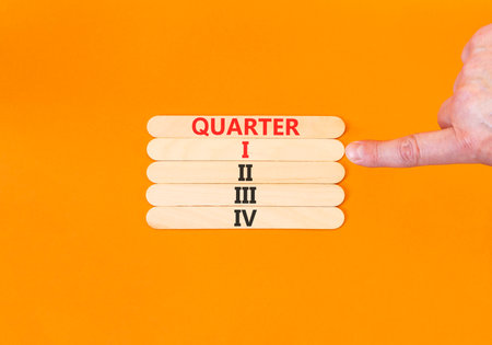 1st first quarter 1 symbol. Concept word Quarter 1 on beautiful wooden sticks. Beautiful orange background. Businessman's hand. Business, happy 1st first quarter 1 Q1 concept. Copy space.の写真素材