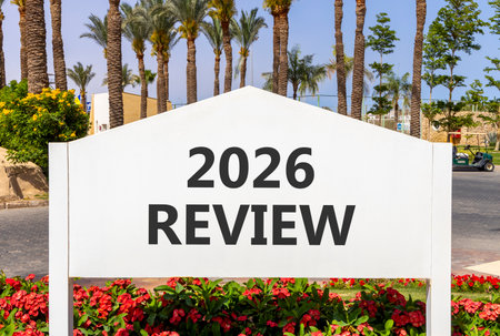 2026 Review symbol. Concept words 2026 Review on beautiful white road sign. Beautiful palm trees...