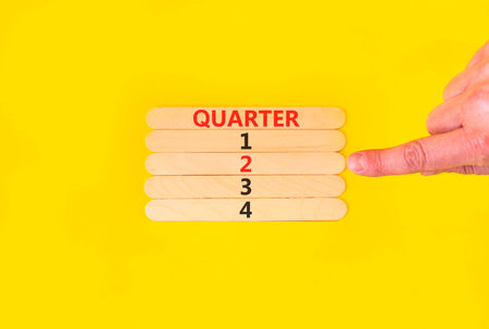 2nd second quarter 2 symbol. Concept word Quarter 2 on beautiful wooden sticks. Beautiful yellow background. Businessman's hand. Business, happy 2nd second quarter 2 Q2 concept. Copy space.の写真素材