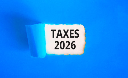Taxes 2026 new year symbol. Concept words Taxes 2026 on beautiful blue paper. Beautiful yellow paper background. Business and taxes 2026 new year concept. Copy space.の写真素材