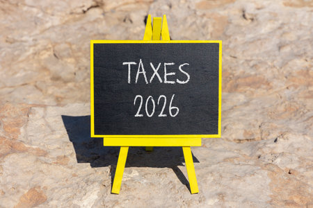 Taxes 2026 new year symbol. Concept words Taxes 2026 on beautiful black blackboard. Beautiful stone...